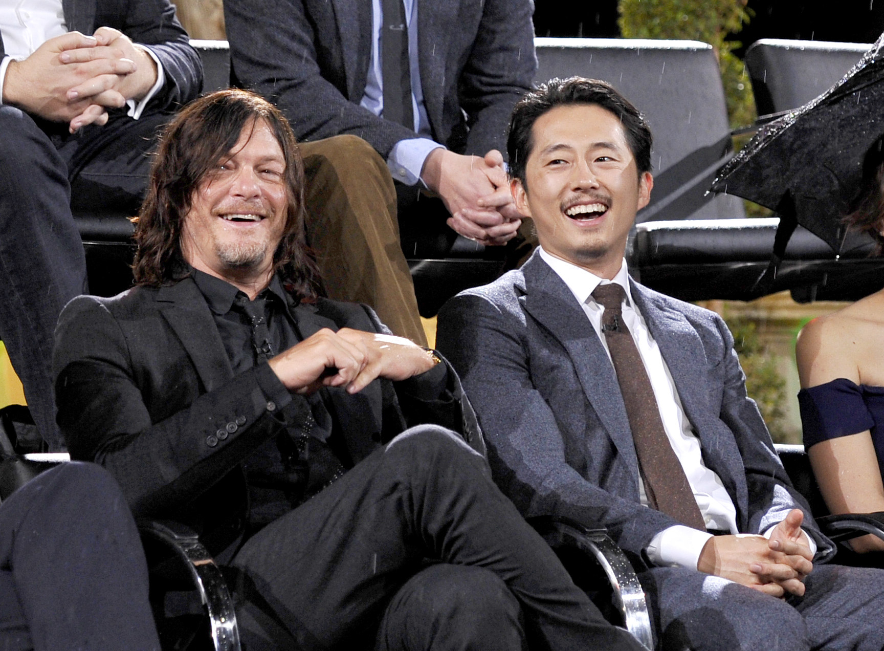 Steven Yeun and Norman Reedus sitting together at a panel