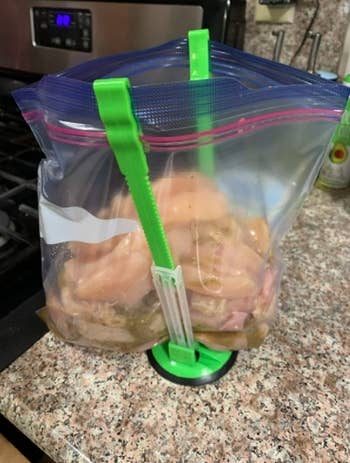 A reviewer photo of a bag holder keeping a bag full of chicken upright
