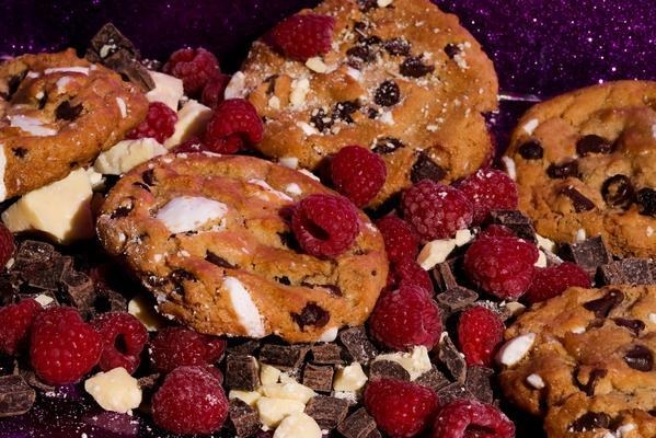 Multiple cookies with white and dark chocolate chunks and raspberries 