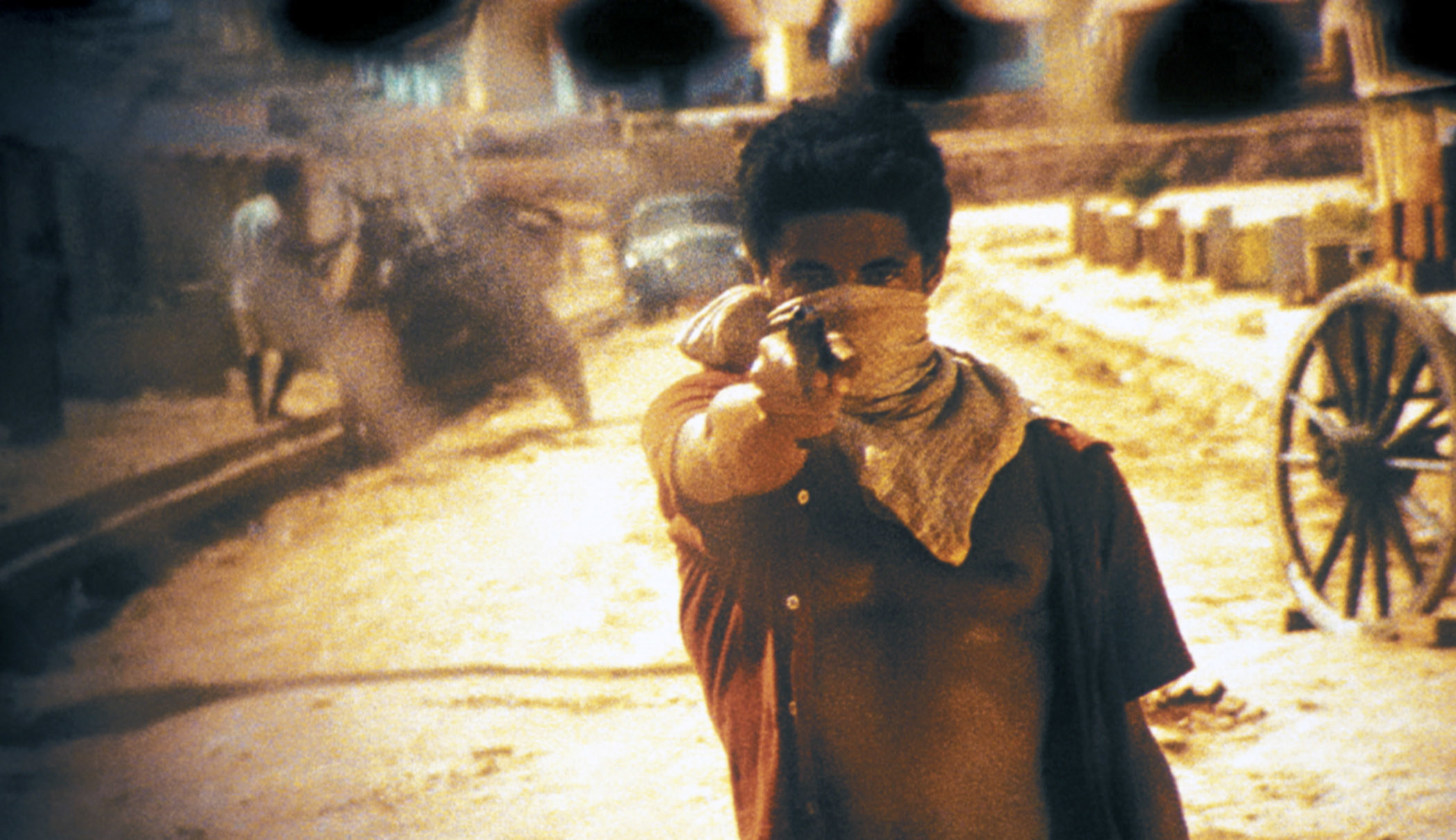 A young boy pointing a gun at the camera 