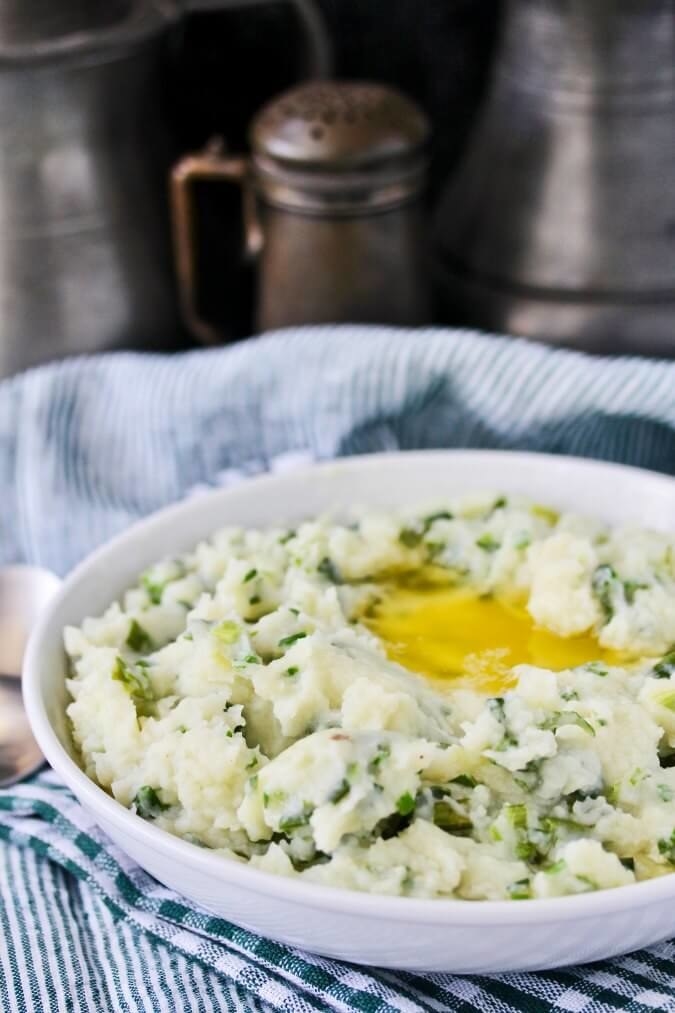 A bowl of Irish mashed potatoes with scallions, chives, and butter.