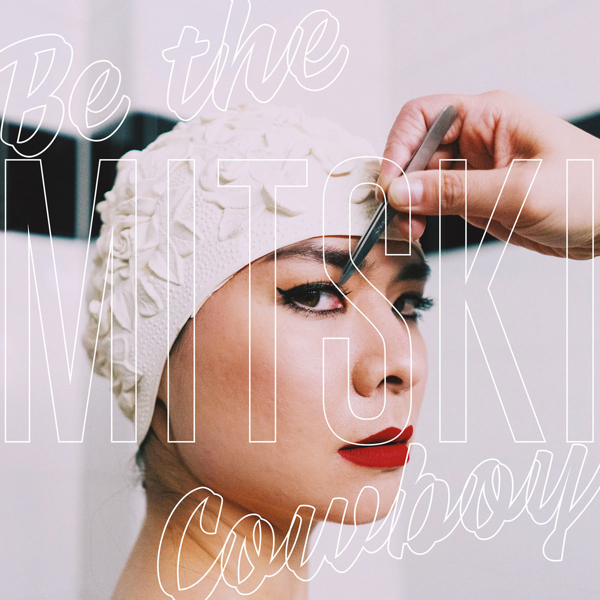 album cover for &quot;be the cowboy&quot; by mitski, which is a woman wearing lipstick and eyeliner, looking over her shoulder at the camera