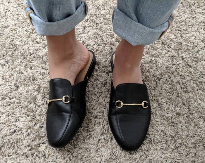 reviewer wearing the black loafers with gold chain design