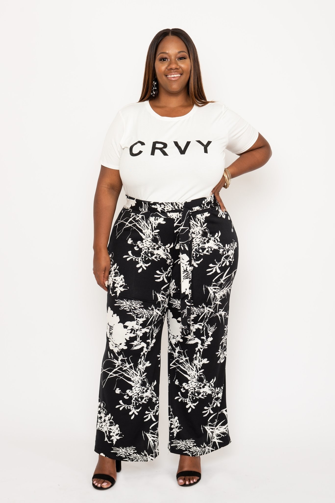 a plus size model wears the black printed wide leg pants with a white tee that reads 