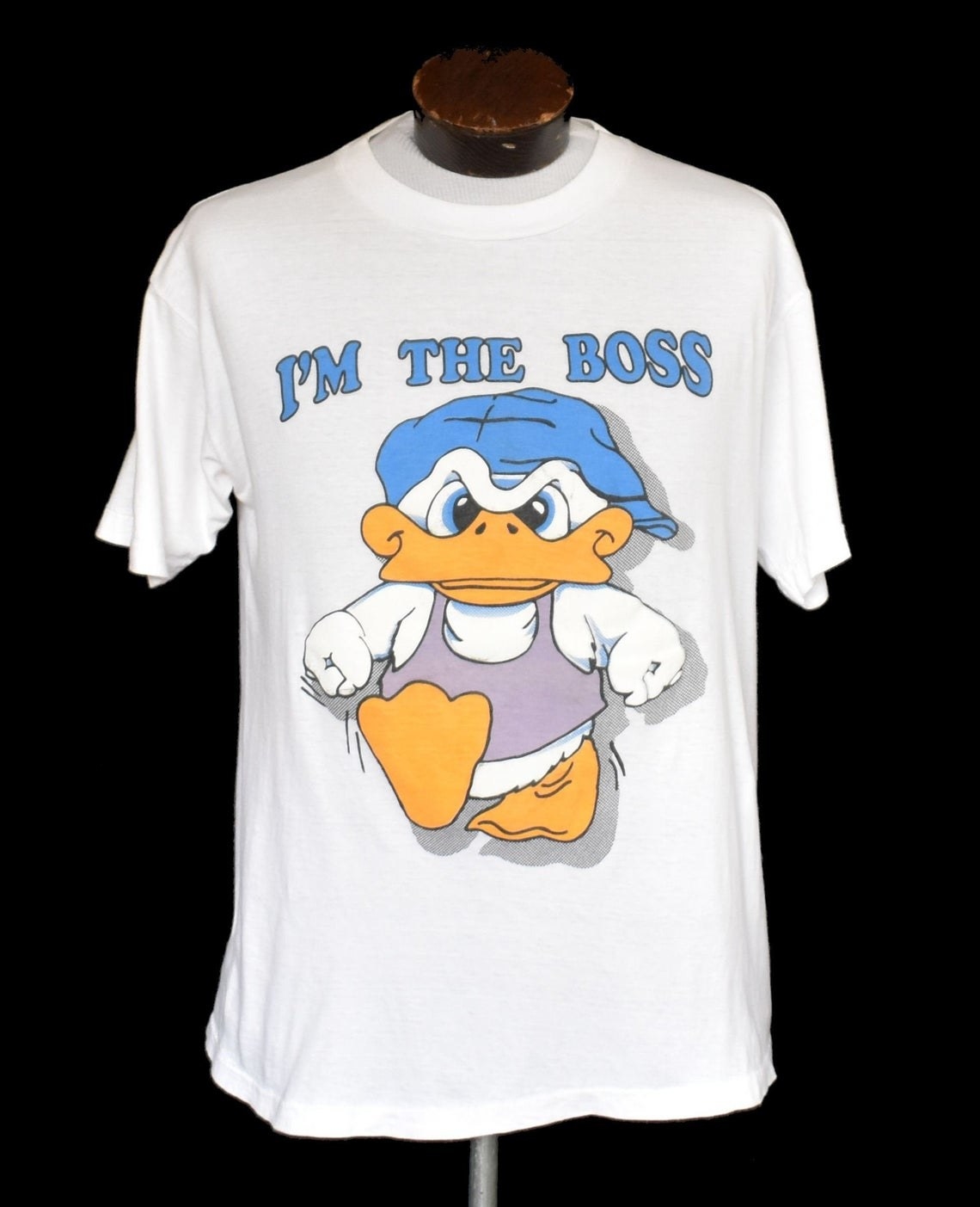 A white T-shirt with a duck wearing a tank top and backwards cap on it with &quot;I&#x27;m the boss&quot; written above it