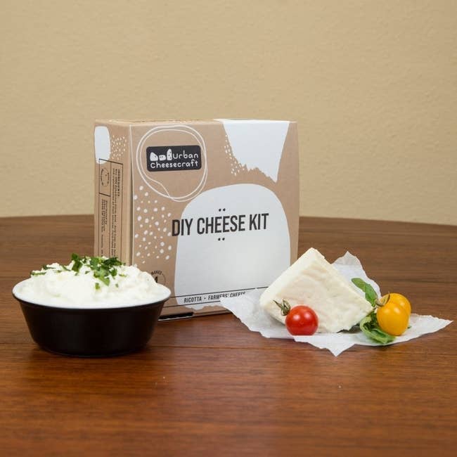 The DIY cheese set box with supplies and the cheese on a table 