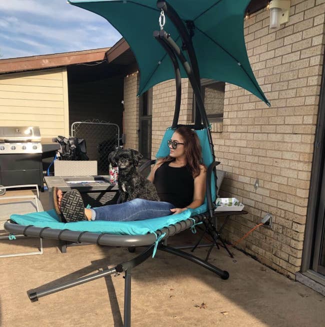 reviewer in chaise lounge chair suspended off the ground with an umbrella for shade