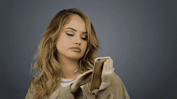 A woman swiping through her phone, looking bored