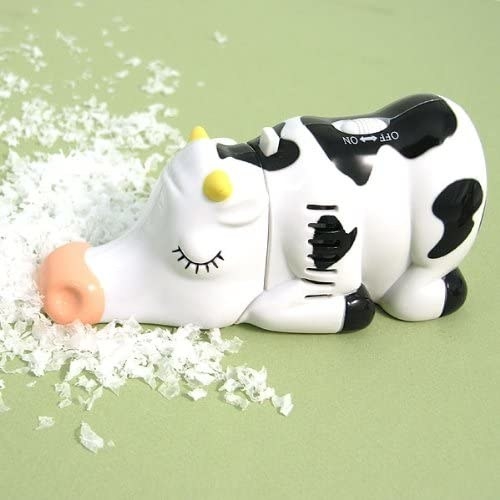 A cow-shaped tabletop vacuum next to crumbs