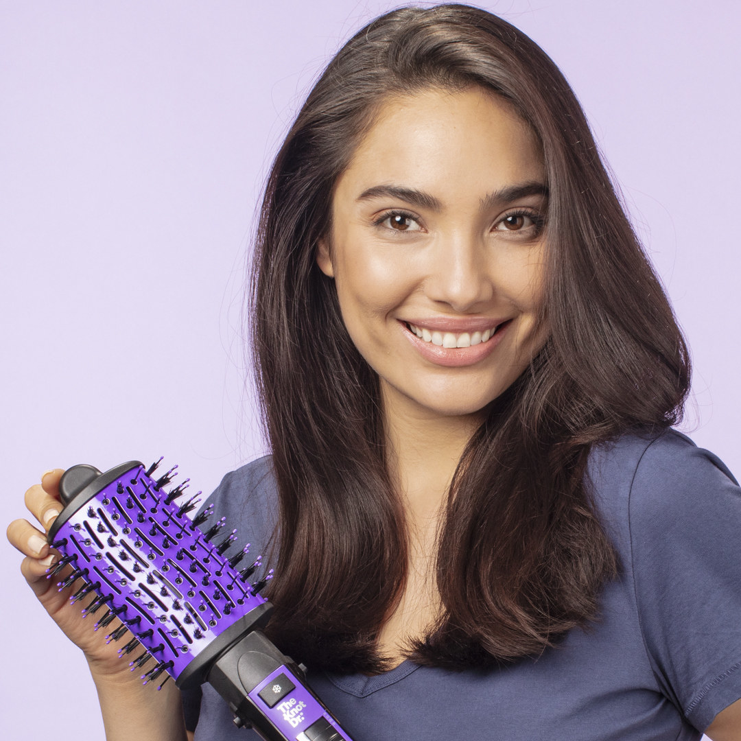 Woman smiles while holding Knot Dr.® All-In-One Dryer Brush
