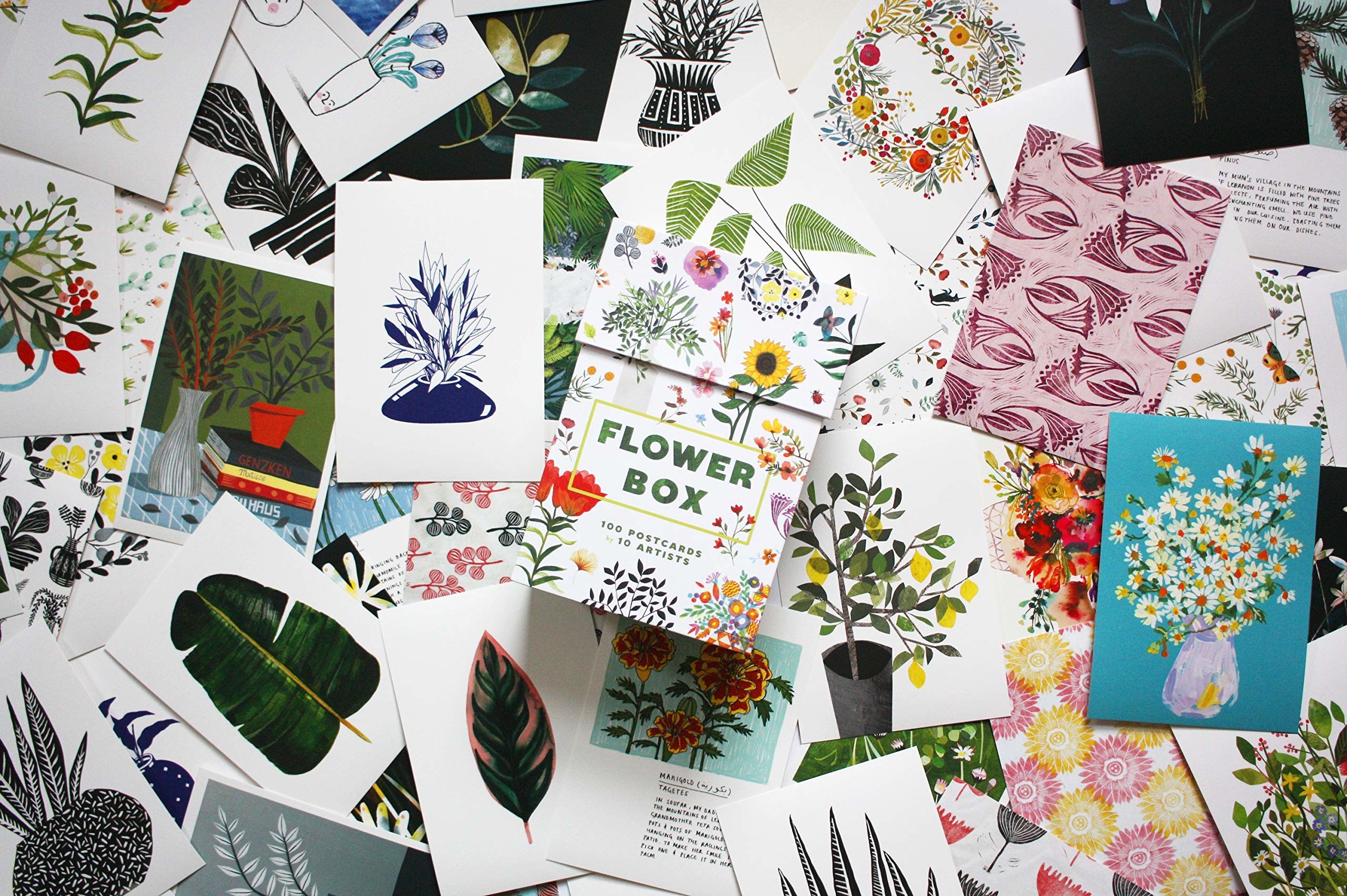 Box of cards on top of a table completely filled with the different post card designs
