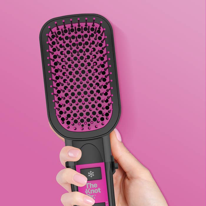 Close up of hand holding the Knot Dr.® All-In-One Smoothing Dryer Brush. 