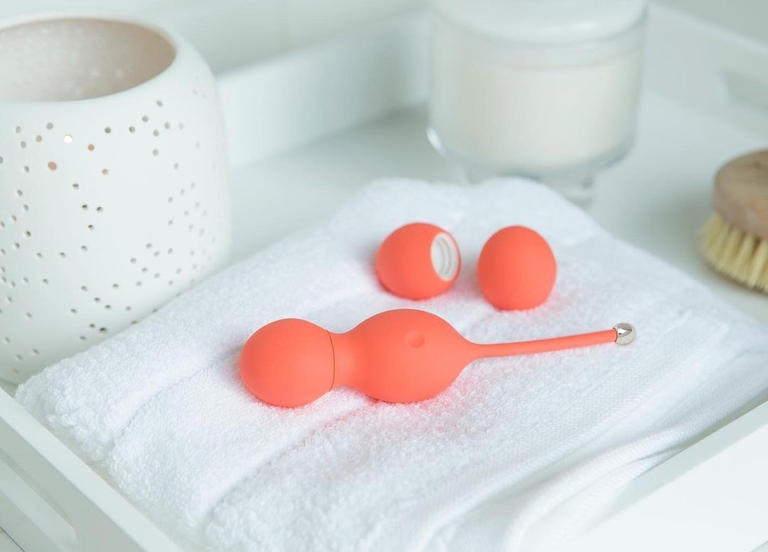 the bloom by we-vibe and its two progressive weights atop a folded white towel