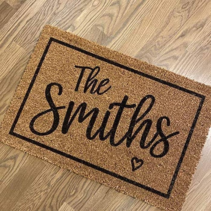 a brown door mat with a black border and &quot;the smiths&quot; written in script with a small black heart under it