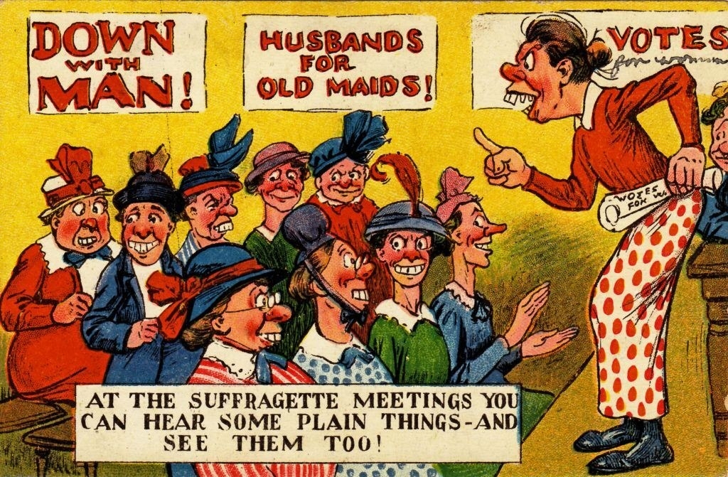 &quot;At the Suffragette meetings you can hear some plain things, and see them, too&quot; written underneath women at a meeting, with &quot;Down with man,&quot; &quot;Husbands for old maids,&quot; and &quot;Votes,&quot; written on posters behind them