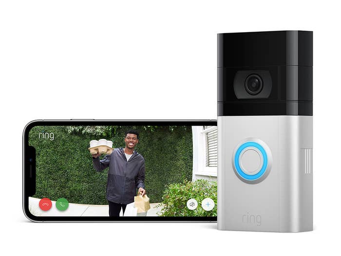 The Ring Video Doorbell next to a phone, showing video of a man holding a delivery of coffee