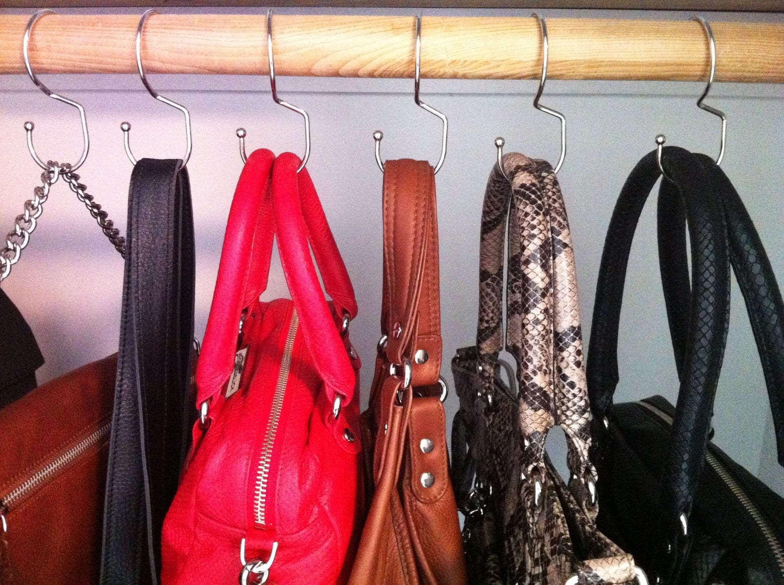 Six silver small hooks holding purses in a closet