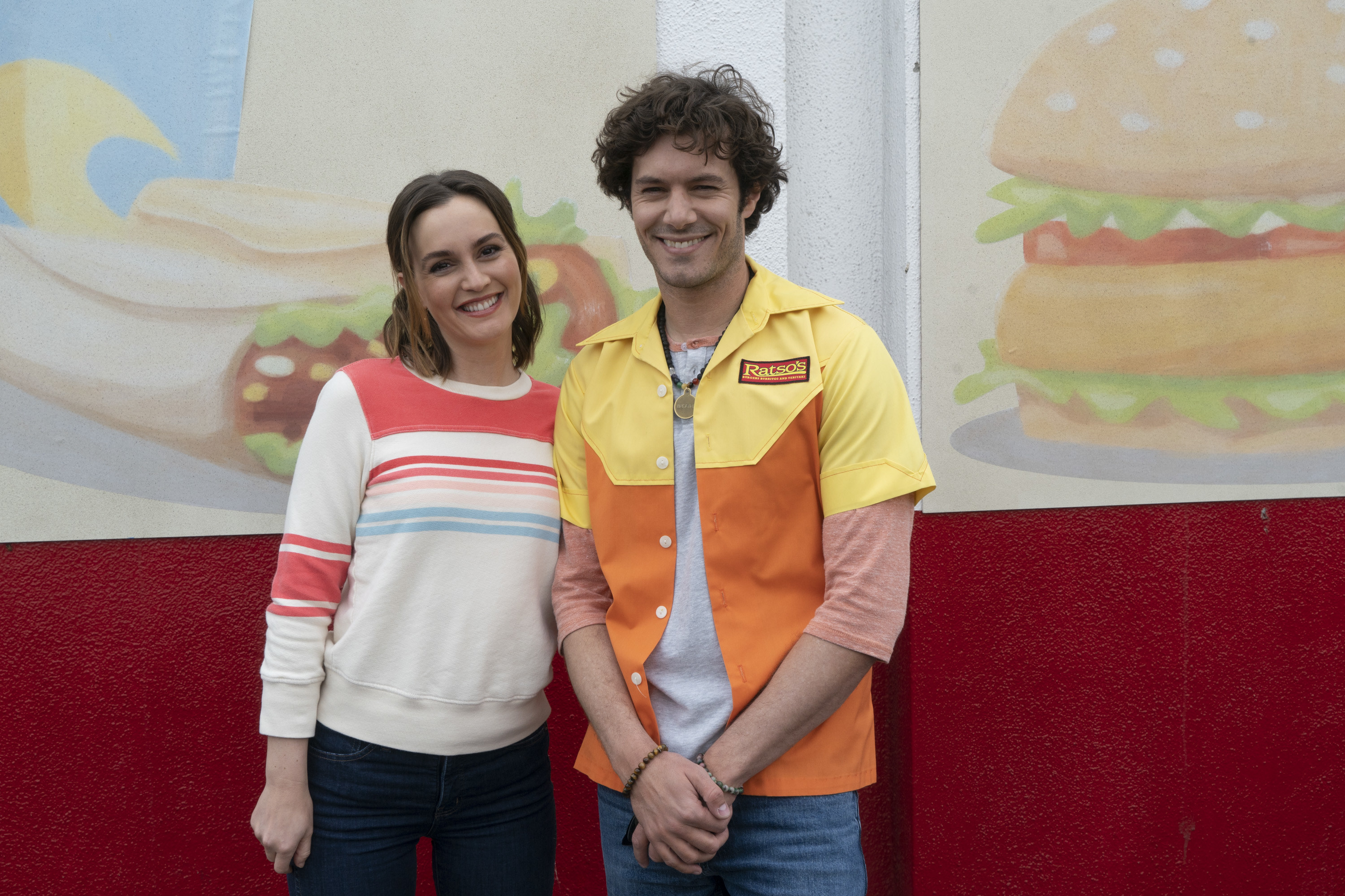 Brody and Meester standing in front of a mural of food in the TV show Single Parents