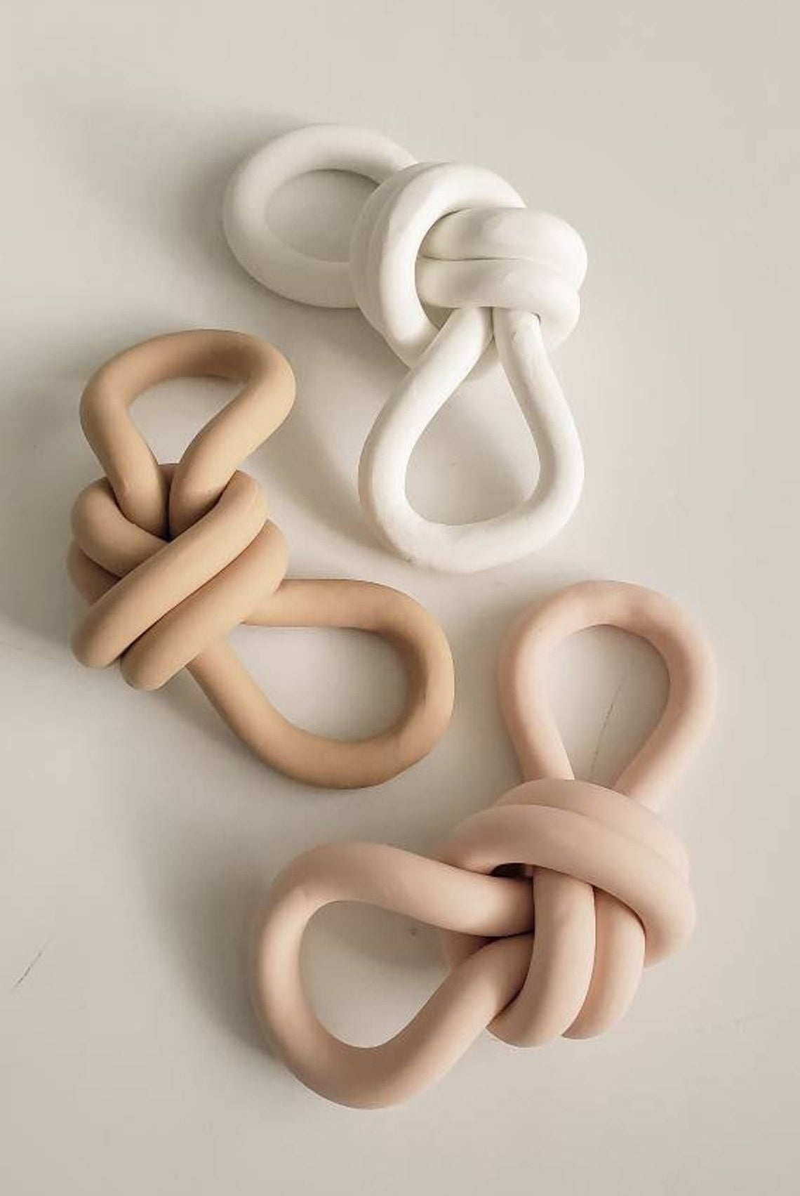 Three knots that look like rope. All are made of different colors of clay. 