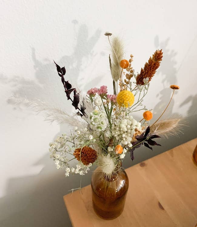 Several different stems of flowers arranged in an amber bottle 