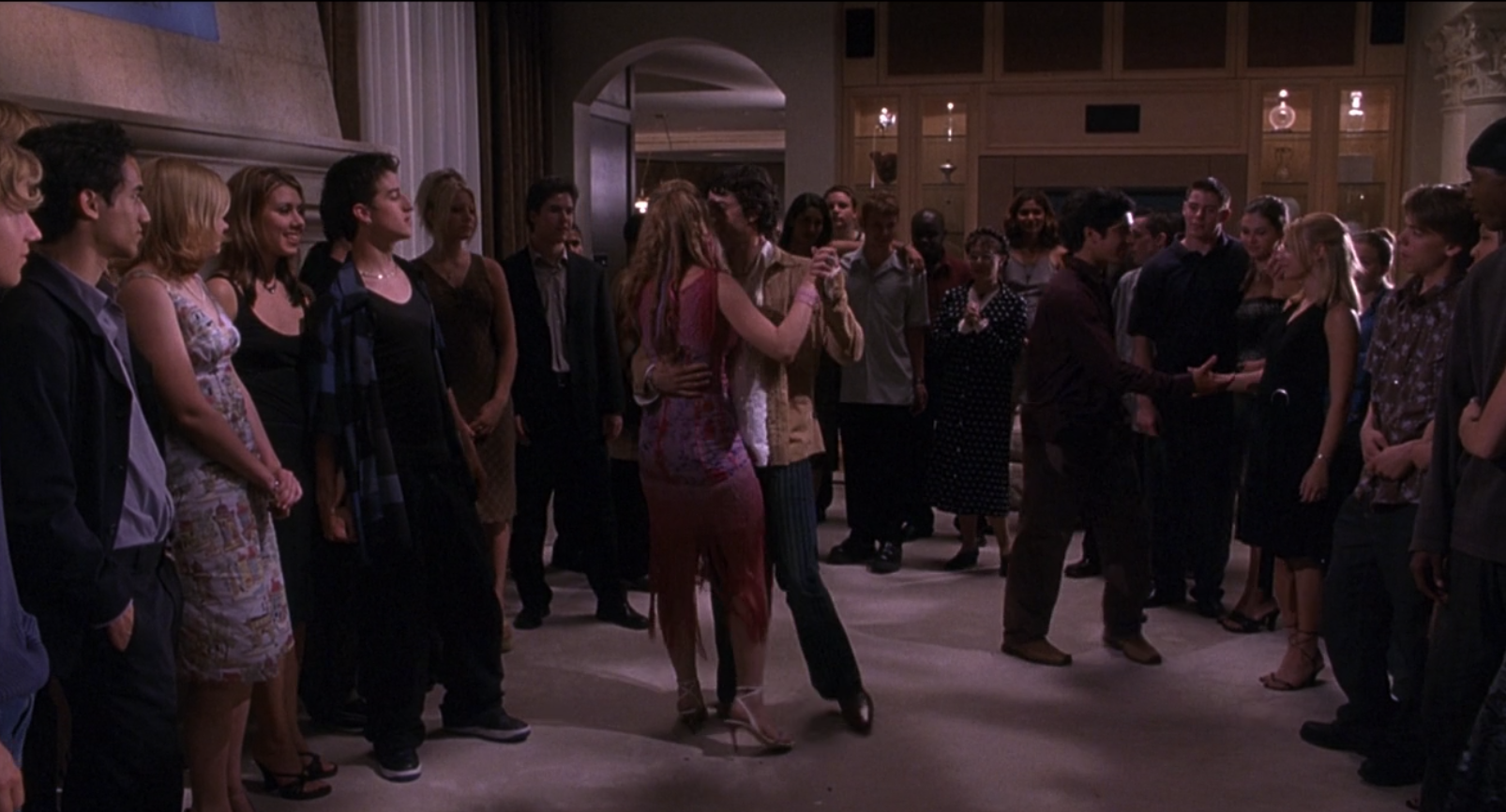 Lola and Stu Wolf slow dancing in the room of a teen party 