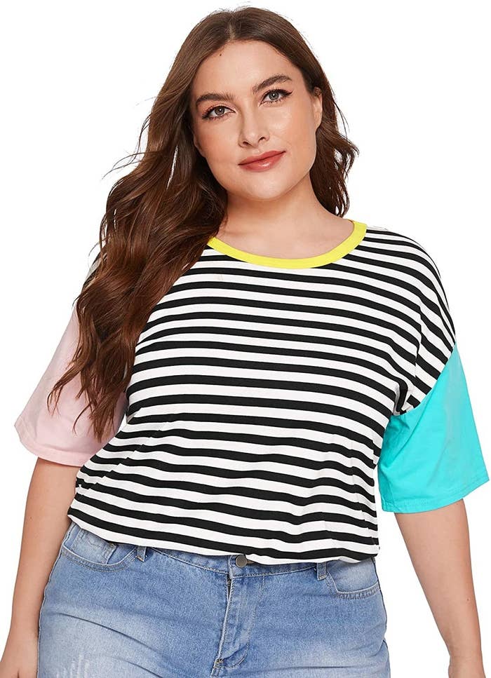 Model wearing black and white striped tee with pink and blue sleeves