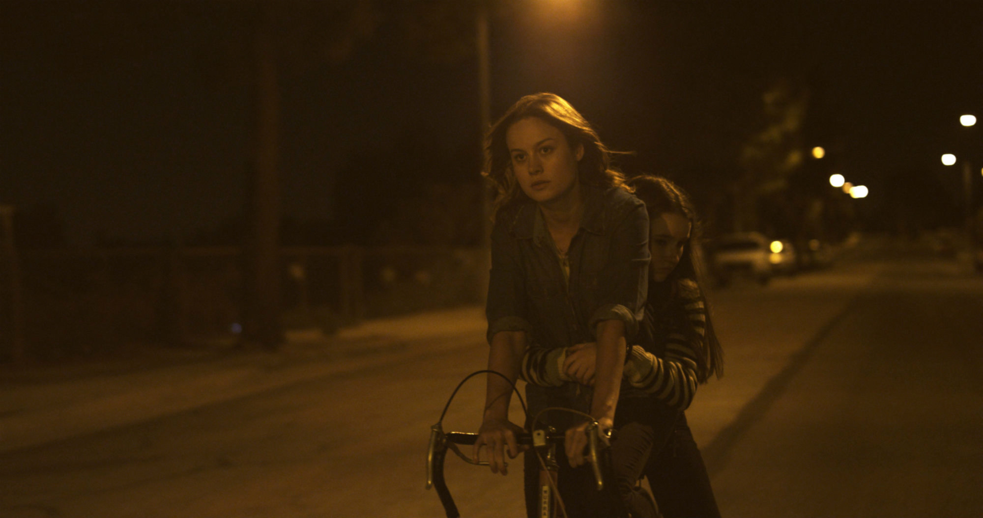 Brie Larson and Kaitlyn Dever riding a bike at night
