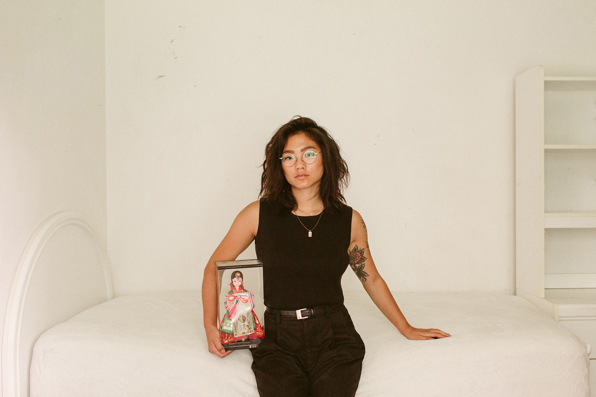 A woman sitting on a bed with an asian figurine