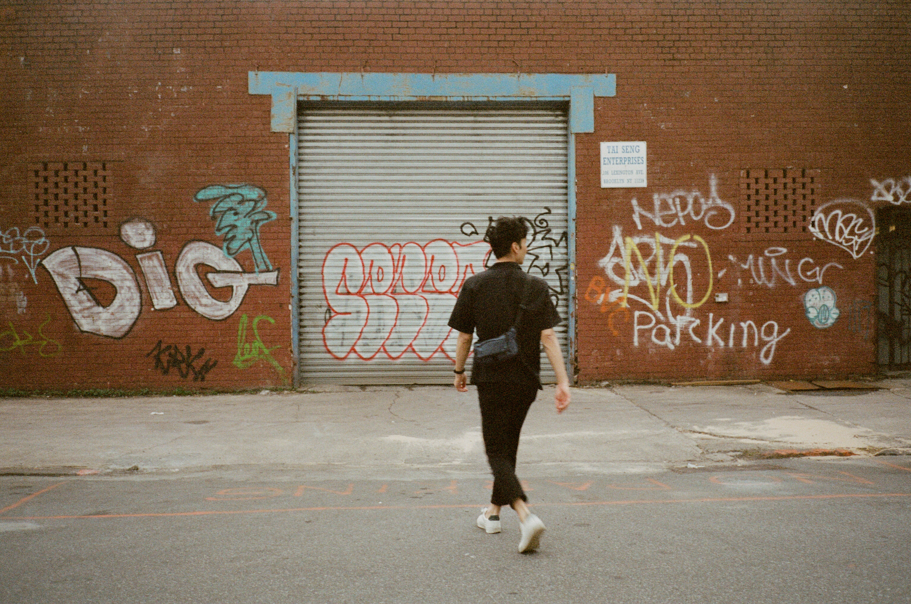 A man walks towards a wall with grafitti