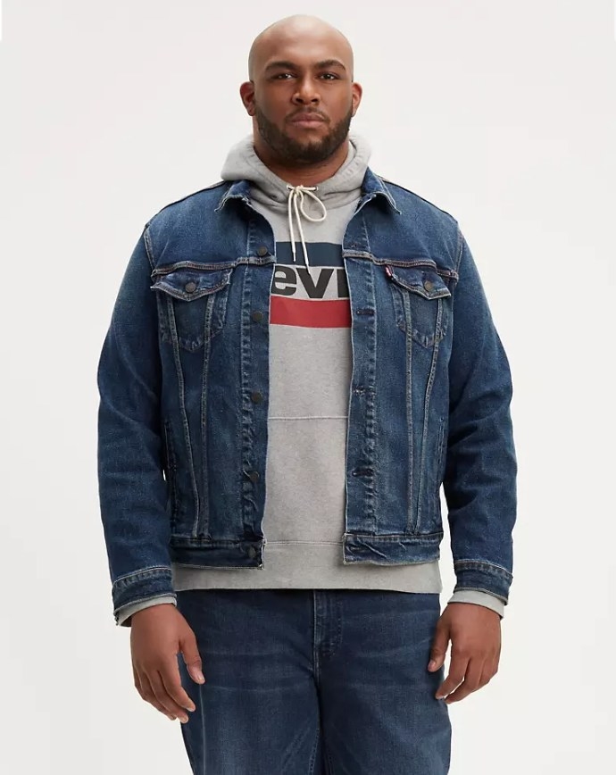 Model wearing dark wash trucker jacket with gray sweatshirt and matching jeans