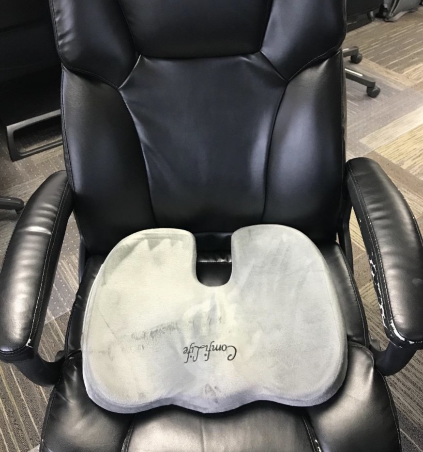 The grey memory foam cushion on a black leather office chair
