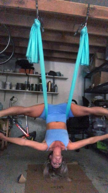 reviewer does a headstand split upside down using the same aerial yoga hammock in their garage