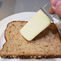 hand using it to butter a piece of bread