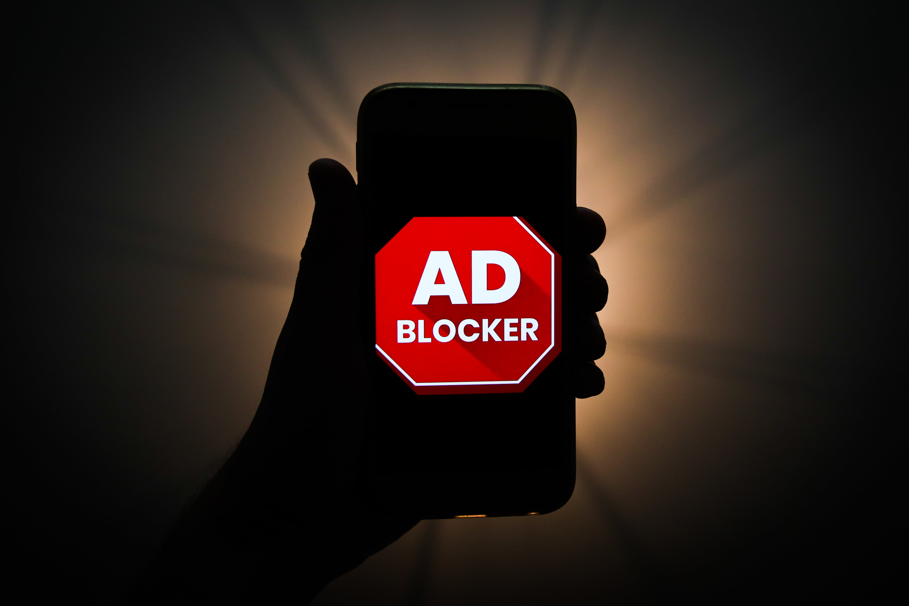 Ad blocker logo shown on the silhouette of a smartphone 