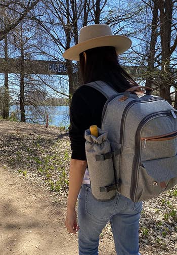 a reviewer photo of someone walking on a trail wearing the backpack 