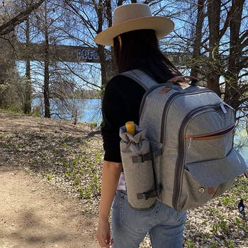 a reviewer photo of someone walking on a trail wearing the backpack 