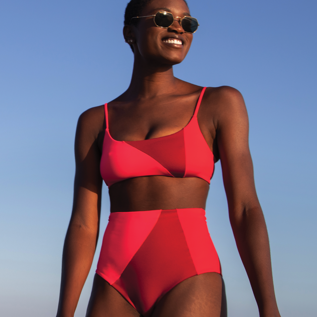 model wearing the suit with high waisted bottom and spaghetti strap top with colorblocks of pink and red