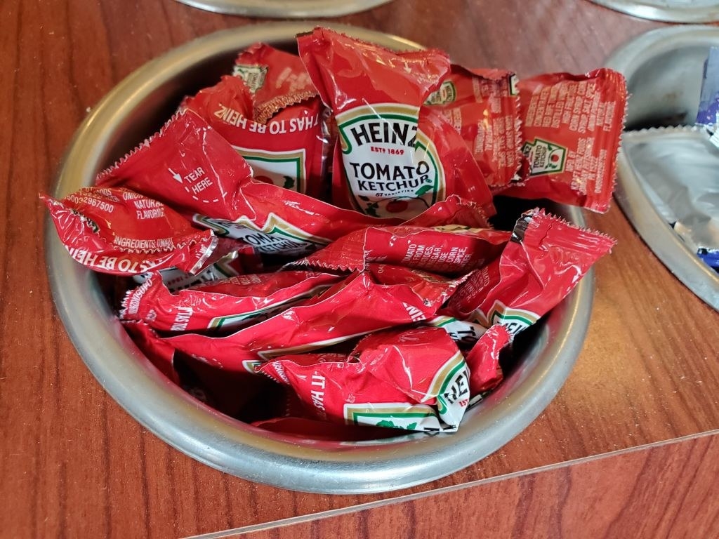A bowl filled with a bunch of Heinz brand ketchup packets