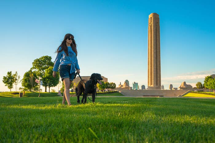 A woman and her dog walk past the National WWI Museum and Memorial
