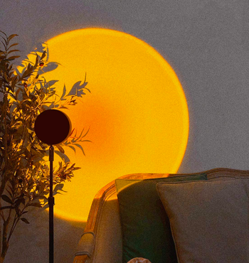 Upright lamp projecting round orange and yellow light onto wall 