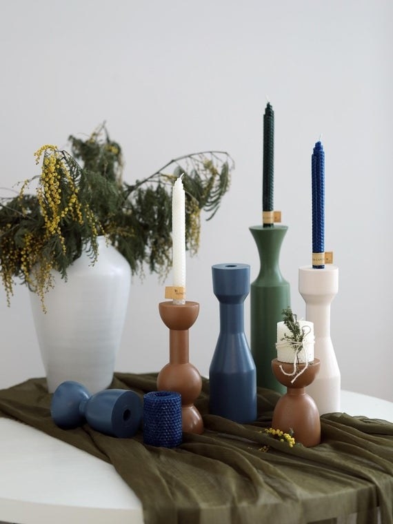 assorted brown, navy, green, and white wood candlestick holders on table