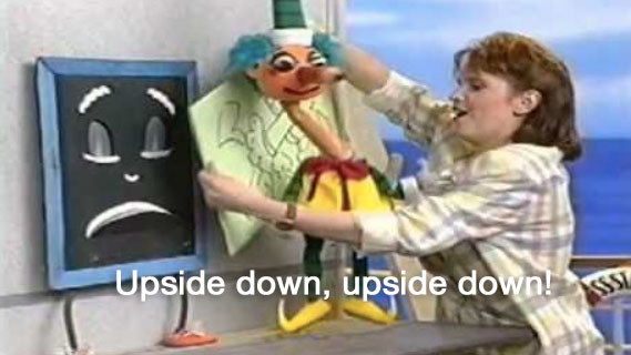 Blackboard, Mr Squiggle, and a woman stand on a set that looks like a boat with the caption &quot;upside down, upside down&quot;
