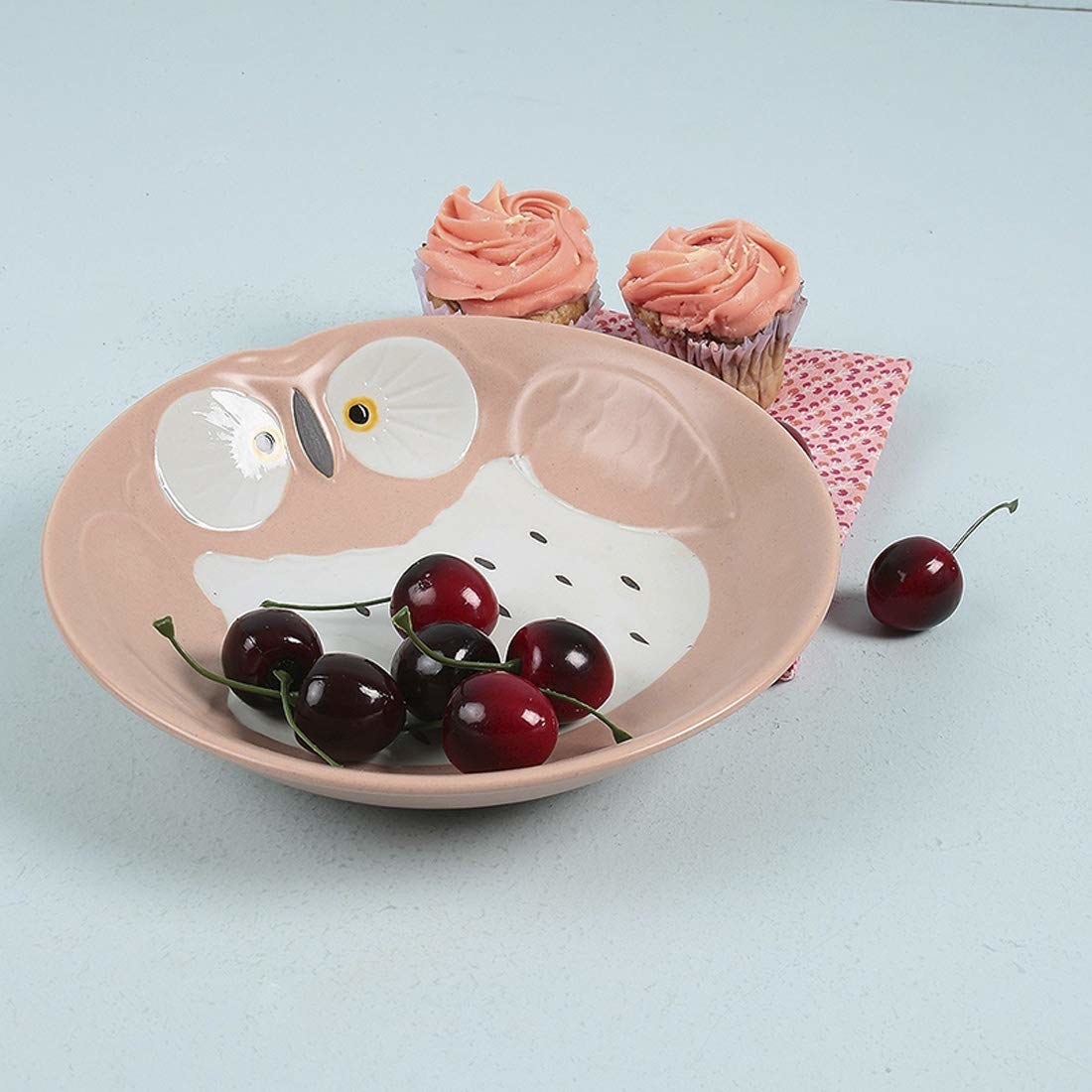 A ceramic owl plate with cherries in it 