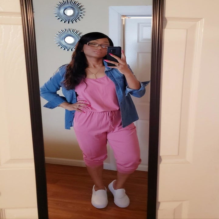 a reviewer photo of the jumpsuit in pink worn with a denim shirt