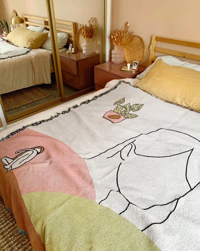 large throw blanket with an illustration of a head, plant, and pink and green colors
