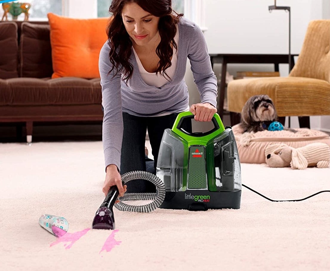 A person cleaning fruit punch off of a carpet with the deep cleaning machine 