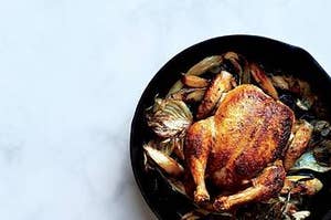 Roasted chicken on a bed of vegetables in a cast iron pan