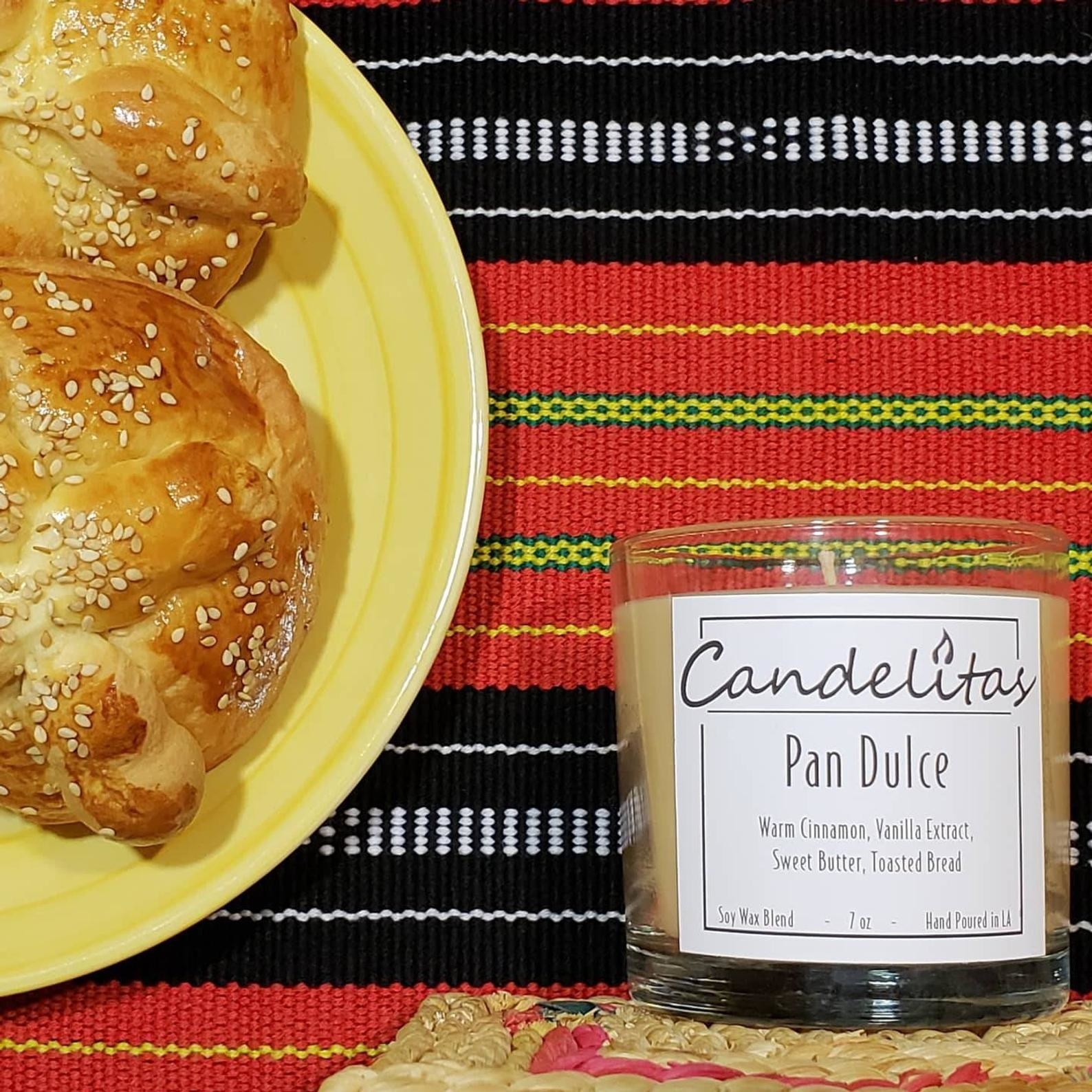 The candle next to a plate of pan dulce