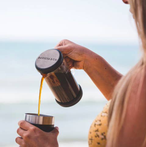 A person using the press/infuser to pour themselves a cup of coffee