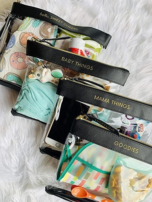 three clear zippered bags with a leather band at the top that has gold labels. The bags are labeled &quot;hello, sweet cheeks,&quot; &quot;baby things,&quot; &quot;mama things,&quot; and &quot;goodies&quot;